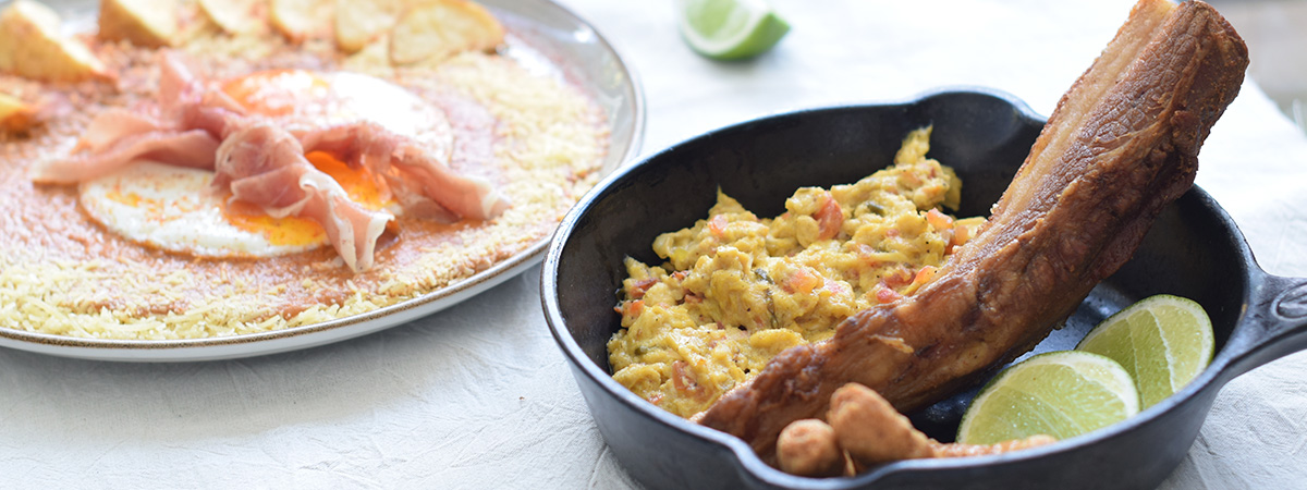 Cacerola Campesina con chicharrón, huevos pericos y chorizos, junto a Huevos Estrellados con jamón serrano y papas rústicas.